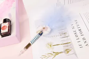 Detail view of an elegant blue feather glass dip pen set with ink and pink gift box