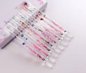 Close-up of elegant glass dip pens filled with dried flowers and colorful glitter.