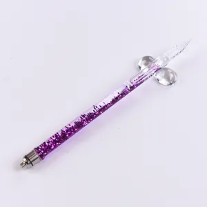 Elegant purple glitter glass dip pen resting on a clear glass pen holder detail view