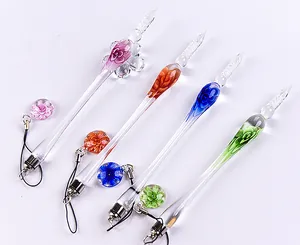Detailed view of four colorful handmade glass dip pens with floral patterns and charms.
