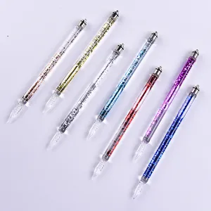 Set of colorful handmade glass dip pens with shimmering glitter liquid on a white base.