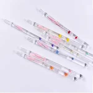 Detail shot of handmade glass dip pens with colorful dried flowers inside.