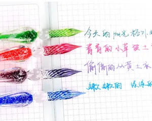 Macro detail of colorful glass dip pen tips showing vibrant ink strokes on grid paper
