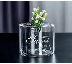 Close-up detail of a cylindrical clear glass vase with artistic white text engraving