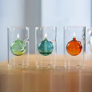 Vista detallada de tres lámparas de aceite de vidrio de colores con llamas parpadeantes