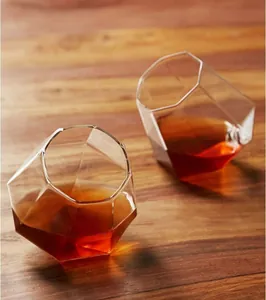 Nahaufnahme von zwei diamantförmigen geometrischen Whiskeygläsern auf einem Holztisch.