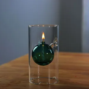Vista detallada de una lámpara de aceite creativa de esfera de vidrio verde en soporte.