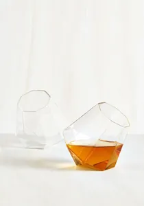 Detailaufnahme eleganter Whiskeygläser in Diamantform auf weißem Holzhintergrund
