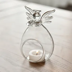 Detailed view of transparent angel-shaped glass vase with a burning candle inside