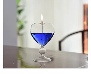 Detailed close-up of a heart-shaped glass oil lamp with blue fuel and a lit flame