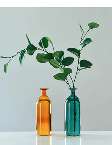 Teal and amber glass vases with green leaves on a clean white table decoration