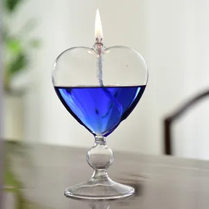 Elegant heart-shaped clear glass oil lamp with vibrant blue liquid and flickering flame.