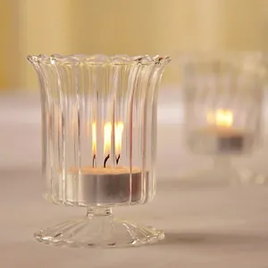 Elegant striped transparent glass candle holder with a warm lit tea light candle inside
