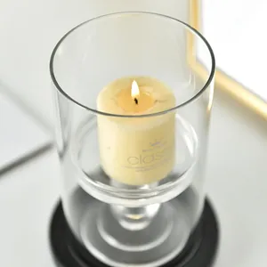 Elegant glass candle holder with lit cream pillar candle for dining home decor