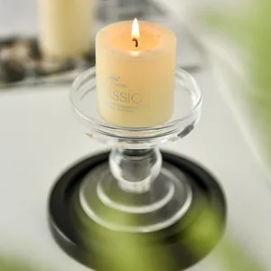 Elegant clear glass candle holder with a lit cream pillar candle for romantic home decor