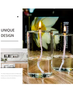 Detail view of handmade clear glass cylindrical oil lamps with lit wicks