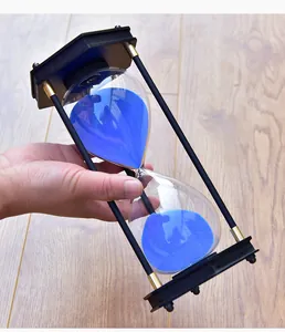 Detailopname van een grote 30-minuten zandloper met blauw zand en een zwart frame.