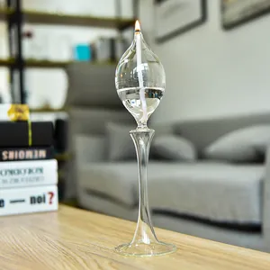Elegante lámpara de aceite de vidrio minimalista con llama sobre mesa de madera