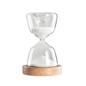Elegant glass hourglass timer with white sand on a round wooden base stand