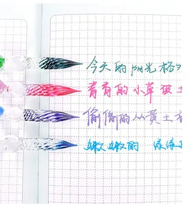 Close-up of four colorful glass dip pen nibs with vibrant handwritten ink samples on grid paper