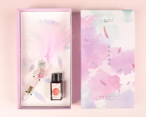Top view of a pink feather glass dip pen and ink bottle inside a purple gift box.