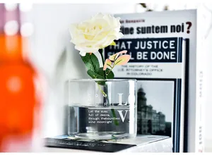 Close-up of a creative transparent glass vase with elegant 'LOVE' lettering and a white rose.