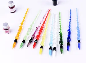 Close-up detail of colorful handmade spiral glass dip pens with ink bottles on white background