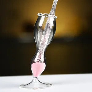 Primer plano de una elegante pluma de vidrio en un soporte decorativo lleno de arena rosa