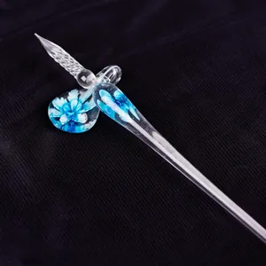 Primer plano de una elegante pluma de vidrio con motivos florales azules y su soporte