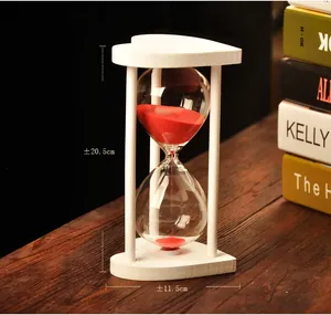 Detailed view of heart-shaped glass hourglass with white wooden frame and red sand
