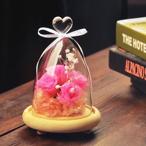 Elegant heart-top glass dome with preserved pink roses and baby's breath on a wooden base
