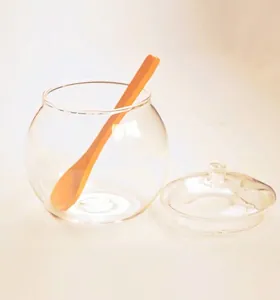 Detail of round clear borosilicate glass sugar jar with lid and orange serving spoon