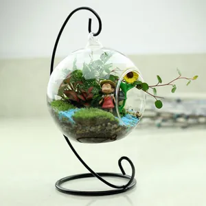 Hanging glass terrarium with Totoro figurine and succulent micro landscape on black stand.