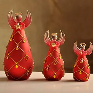 Dettaglio di tre angeli decorativi in vetro smerigliato rosso con finiture in oro