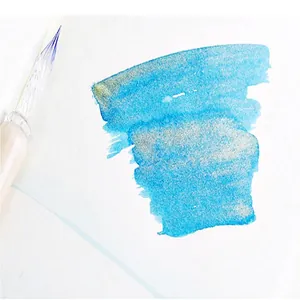 Detailed close-up showing blue shimmering ink swatch with a glass dip pen on paper