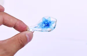 Macro view of a handcrafted glass dip pen nib with a blue embedded flower detail.
