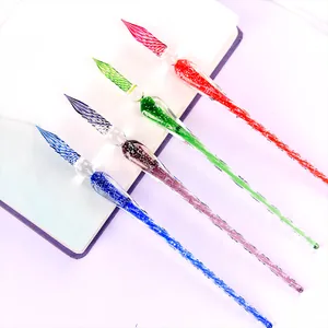 Handmade luminous glass dip pens in four vibrant colors displayed on a white notebook