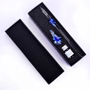 Detailed macro view of handmade blue floral glass dip pen with ink bottle in black box