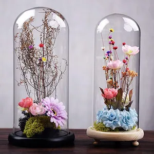 Two elegant glass cloche domes featuring preserved flowers and wooden bases for home decor
