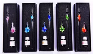 Macro detail of handmade glass dip pen sets with elegant internal floral designs and ink