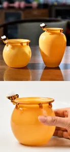 Close-up detail of a warm amber glass honey jar with a cute handcrafted bee ornament