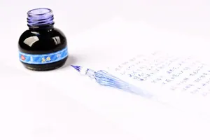 Elegant handcrafted blue glass dip pen shown with black ink and handwritten notes