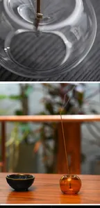 Close-up of a round amber glass incense holder with a burning stick in a Zen setting