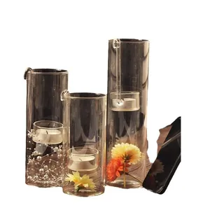 Set of three transparent cylindrical glass candle holders with hanging tea light cups