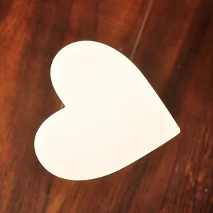 Creative heart-shaped glass hourglass with white wood frame on dark wooden surface