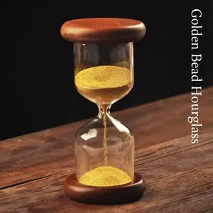 Elegant gold bead hourglass timer with dark wood base on a rustic wooden table background