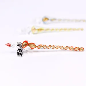 Detailed view of a handmade glass dip pen with a red nib and orange spiral pattern