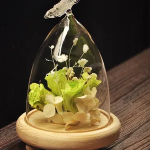 Elegant butterfly glass dome featuring preserved green roses on a rustic wooden base