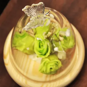 Elegant glass dome with crystal butterfly and green preserved roses on wooden base