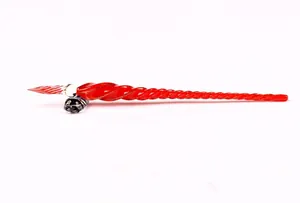 Detailed macro view of a red spiral glass dip pen resting on a sleek glass pen rest